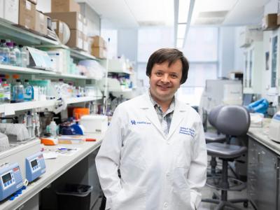 UK researcher Jeremy Wood, pictured in his lab wearing a white coat, is co-leading research that may provide answers for why so many COVID-19 patients experience blood clotting. 