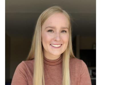 Headshot of Ashley White, an undergraduate white woman with long, straight blonde hair. She is wearing a dusky rose-colored turtleneck shirt. 