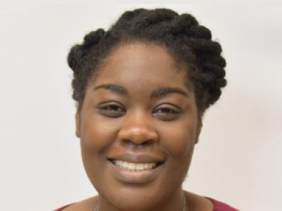 Headshot of Dr. Brittany Smalls, a Black woman in her 30s. She's smiling at the camera and wearing a dark pink shirt, with her hair twisted back on their side. 