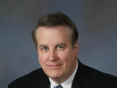 Faculty photo of Dr. Gerald Supinski, a white man in his 50s or 60s with kind eyes, wearing a black suit, white collared shirt, and gray striped tie. 