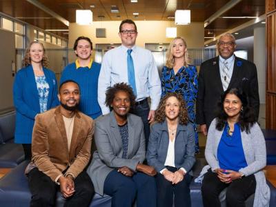Photo shows 9 members of the UK ASCEND team, four seated and five standing behind them. Front row: Justin Moore, Lovoria Williams, Nancy Schoenberg, Shyanika Rose. Back row: Pamela Hull, Jimmy Robinson, Kevin Pearson, Hilary Surratt, Darwin Conwell. Not pictured: Carolyn Lauckner, Misti Salyers-Dunford. Jeremy Blackburn, ResComm