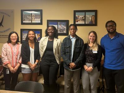 Seven participants in the DREAM and SPARK programs stand side by side in a conference room. 
