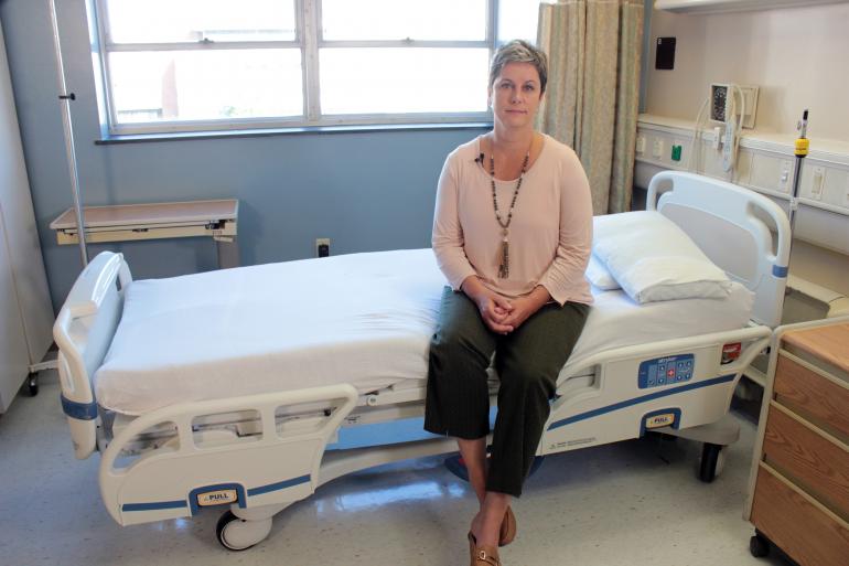 Aime Kunes sits on a hospital bed in the CCTS Inpatient Research Unit