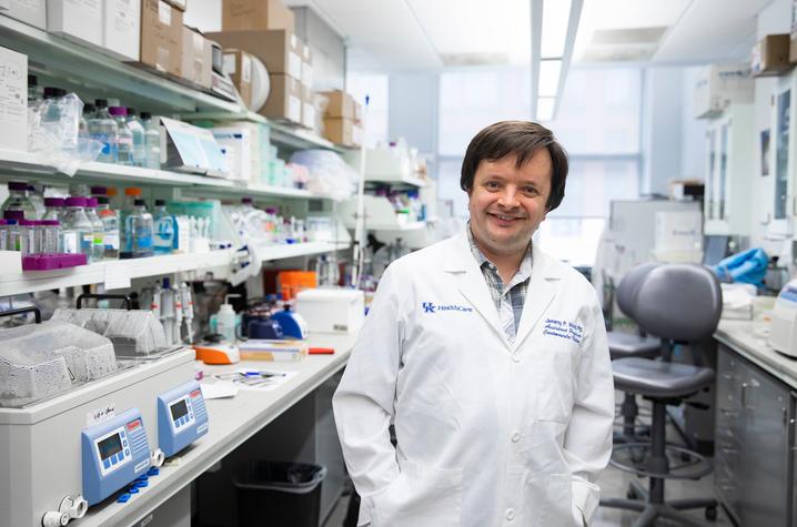 UK researcher Jeremy Wood, pictured in his lab wearing a white coat, is co-leading research that may provide answers for why so many COVID-19 patients experience blood clotting.