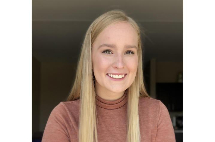 Headshot of Ashley White, an undergraduate white woman with long, straight blonde hair. She is wearing a dusky rose-colored turtleneck shirt. 