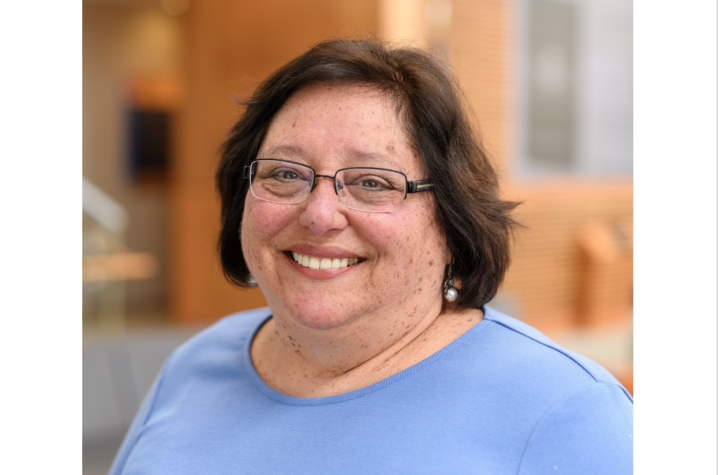 Headshot of Linda Dwoskin, PhD. She's a white middle-aged woman with chin-length dark brown hair, thin-framed rectangular glasses, and pearl earrings. She's wearing a periwinkle shirt and smiling. 