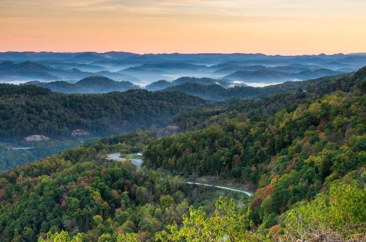 Landscape arial view of Appalachia, the forested mountains in the foreground and blue, misty mountains in the background.
