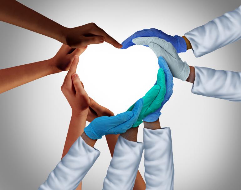 Heart shape made by hands of many skin tones and hands with different medical gloves and wearing white medical coats 