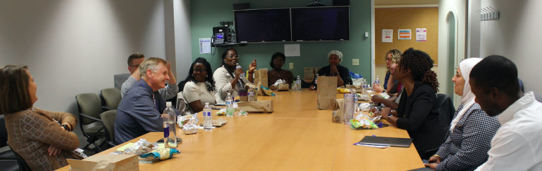 Around a long oval conference table sit CCTS leadership, SPARK and DREAM participants, and mentors. 