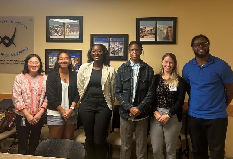 Seven participants in the DREAM and SPARK programs stand side by side in a conference room.