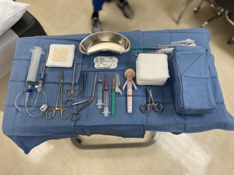 A sterile field tray of tools for a medical biopsy, such as syringes, forceps, and gauze. 