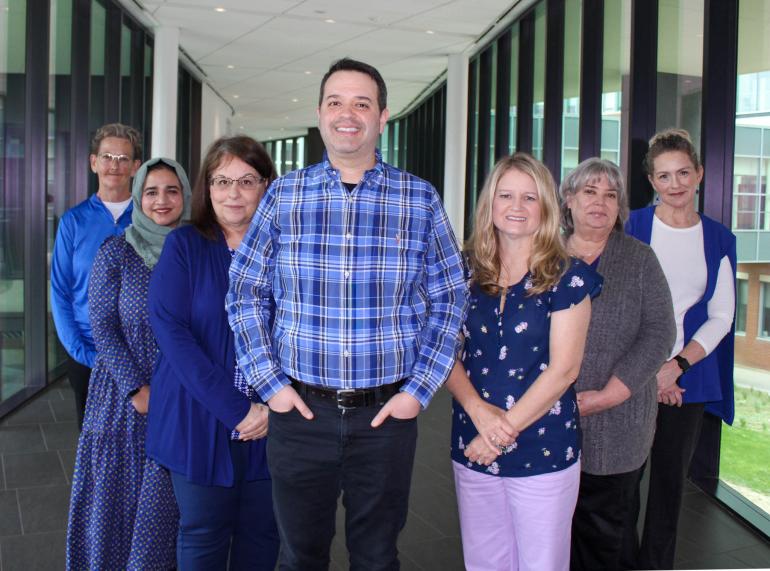 A group photo of the UK CCTS Regulatory Start-Up Support Services team, standing together and smiling in a corridor with glass walls