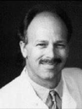 black and white headshot of dr. tom curry, a white man wearing a shirt and tie and medical coat. he has a mustache. the photo appears dated by a couple decades. 