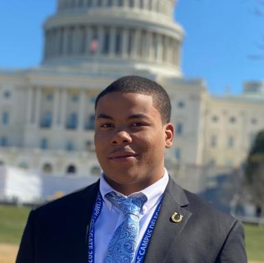 Headshot of Jerron Thomas, a 2021 SPARKler. He's in a suit and tie, standing in front of the Capitol. 