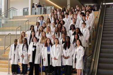 Students in lab coats lined up on stairs