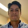 Headshot of Richard Sanchez. He has dark har parted on the left, dark brown eyes, and is wearing a light blue collared button up shirt.