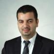 Headshot of Elie Abu Jawdeh, MD, PhD. He's has short dark hair, a bit of a widow's peak, and a faint mustache and goatee. He's wearing a dark suit with a white collared shirt and a dark tie with subtle diagonal stripes. 