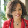 Headshot of Elizabeth Ofili, MD, MPH, FACC, a Black woman with curly hair just past her chin. She's smiling, wearing a red suit jacket, red lipstick, and a stethoscope around her neck. Behind her is a window and plants. 