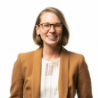 Professional headshot of a Katie Marks, a white woman in her thirties. She's thin with chin-length dark blonde hair, tortoise shell-rimmed glasses, wearing a tan blazer and white blouse. She's in front of a white backdrop. 