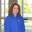 Dr. Krstyle Kuhs, a woman with shoulder-length curly brown hair, smiles at the camera. She's wearing a royal blue zip-up fleece.