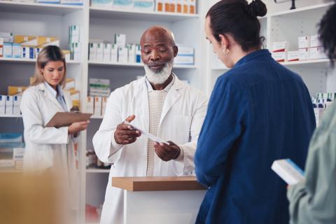 Man at the pharmacy being shown a paper. 