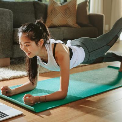 A female on yoga mat interacting with a laptop