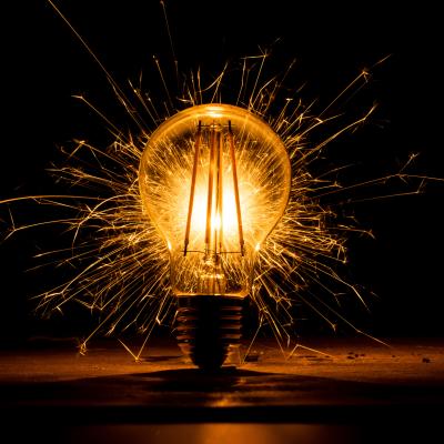 Light bulb sparkling with electricity on a dark background